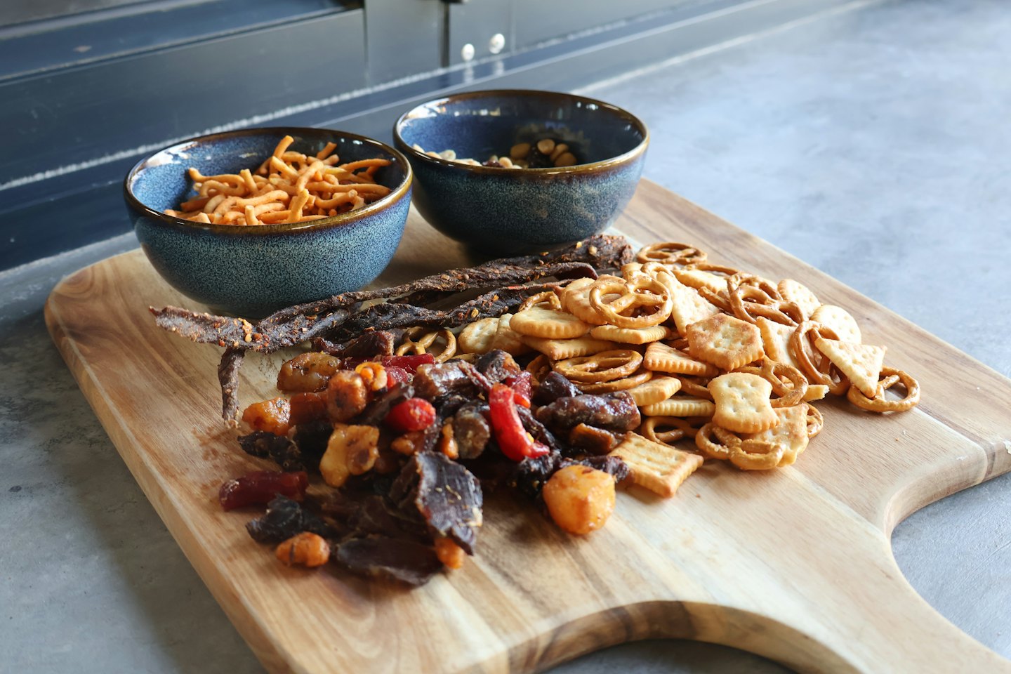 Assorted snacks displayed on a wooden cutting board.
