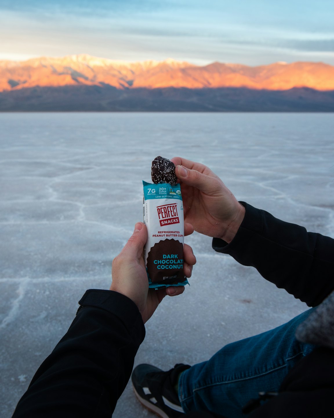 Person holding dark chocolate coconut snack bar on a salt pan.