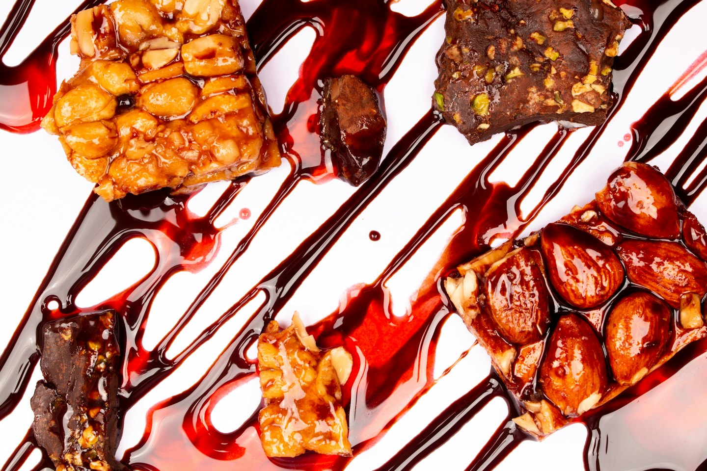 Assorted nut bars and dark chocolate pieces drizzled with syrup.
